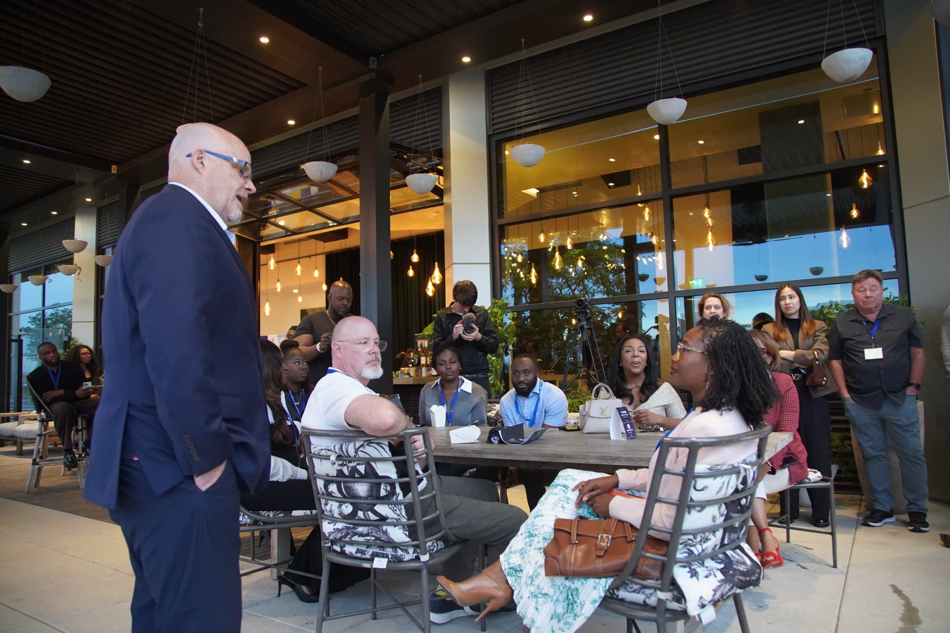Attendees seated and standing at a Tech Catalyst Summit evening, listening to a speaker on a Midtown Atlanta terrace